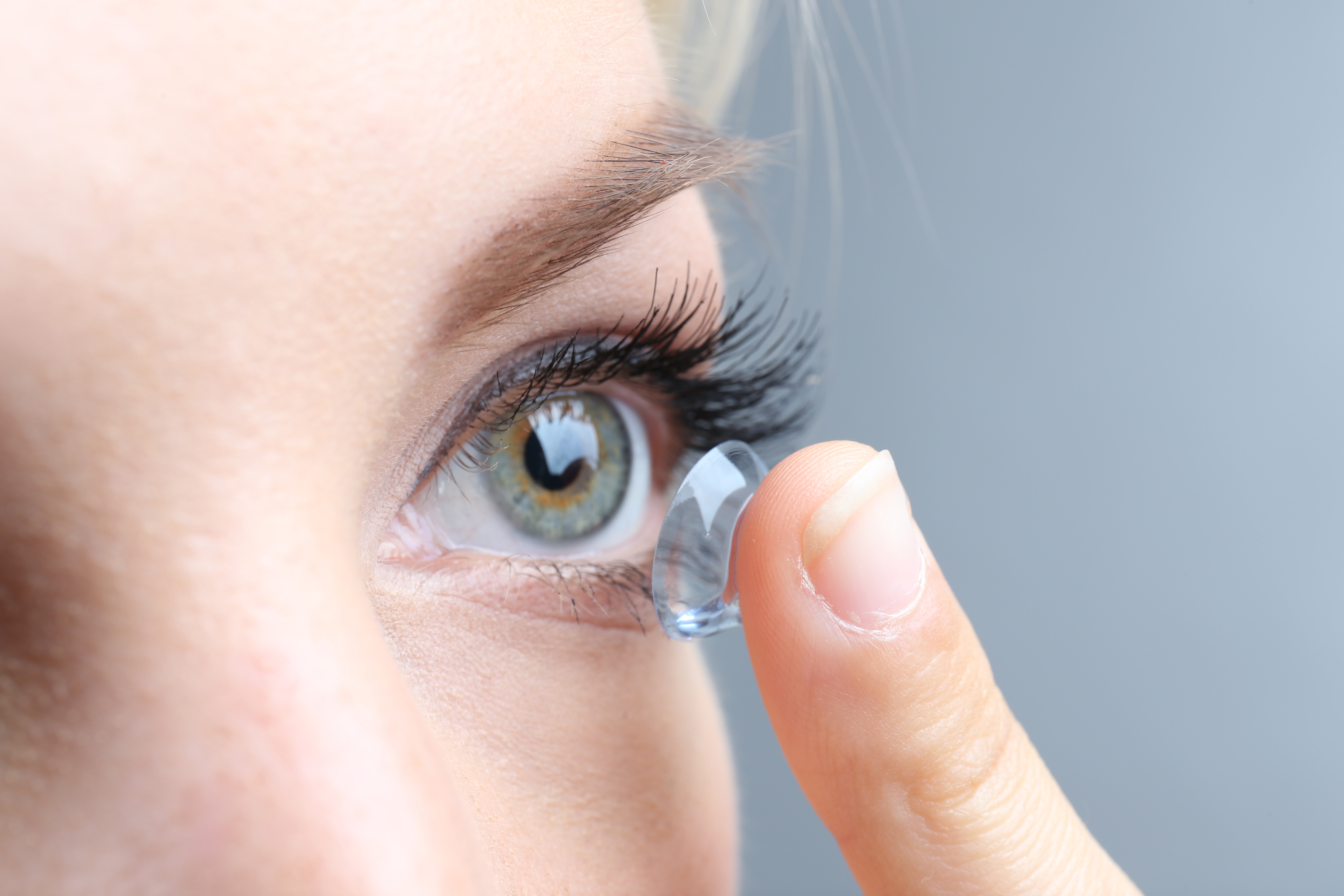 close up on women placing a contact lens in her eye