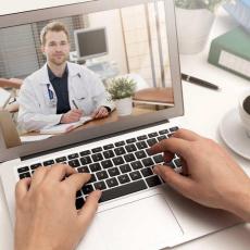 Male doctor on consulting patient through video chat on a laptop computer