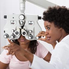 Optometrists uses vision device to test patient's eye sight.