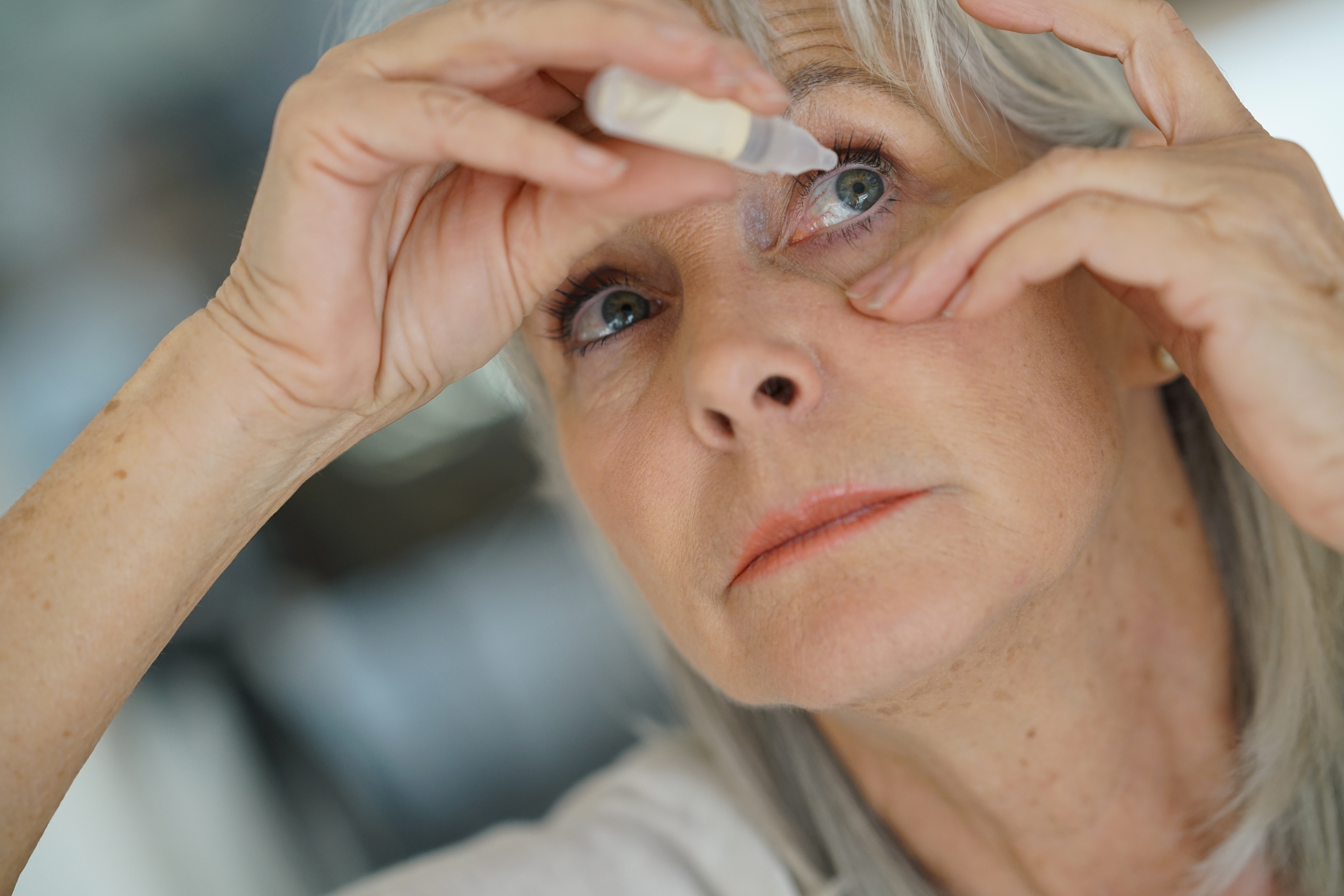 Elderly woman uses eye drops