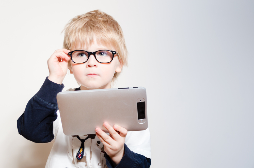 Little boy with glasses uses tablet computer