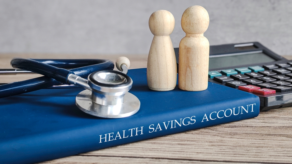 Photo showing a manual with "health savings account" written on the side. Along with a stethoscope on top of it