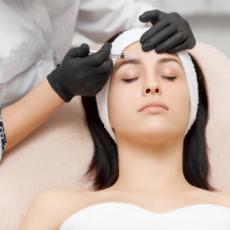 Image of female patient with doctor injecting into her forehead.