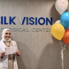 Dr. Rajjoub holds a sign saying "Congratulations" while standing in front of the Silk Vision lobby sign.