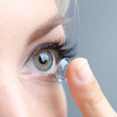 close up on women placing a contact lens in her eye