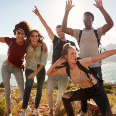 Millennials who had LASIK eye surgery are friends on a hiking trip celebrate reaching the summit and have fun posing for photos