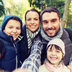 happy family with backpacks taking selfie and hiking and seeing clearly