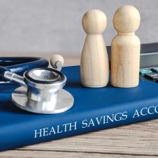 Photo showing a manual with "health savings account" written on the side. Along with a stethoscope on top of it
